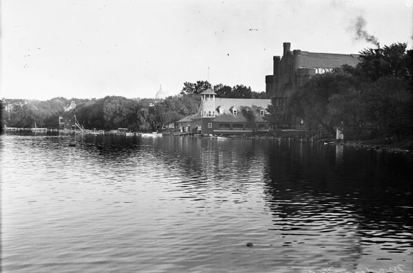 View across Lake Mendota of the University Boat House and Red Gym along the shoreline. The dome of the Wisconsin State Capitol can be seen in the distance.