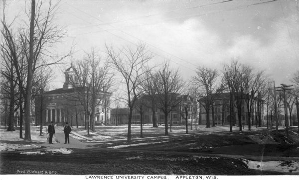 View of Lawrence University campus. Two men stand on the sidewalk in the foreground. Caption reads: "Lawrence University Campus, Appleton, Wis."