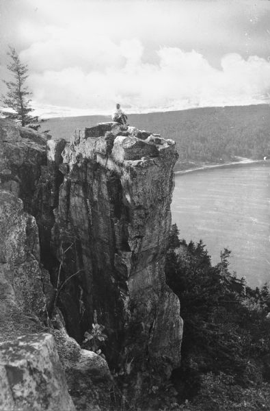 View of of Devil's Lake from Inspiration Point. A man is sitting on top of a rock formation in the foreground.