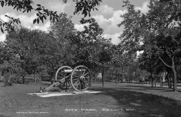 View of City Park featuring a mounted cannon. There are houses and perhaps a church in the far background. Caption reads: City Park, Beloit, Wis."
