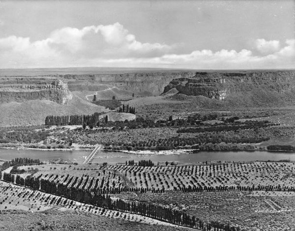 Elevated view of a fertile valley in Twin Falls, Idaho. The Snake River can be seen running through the valley. Geological formations can be seen nearby.