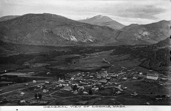 Elevated view of the town in the valley, with houses, other buildings, a bridge, and roads. Caption reads: "General view of Loomis, Wash."
