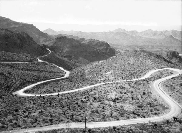Elevated view of an old trail winding through a desert landscape with mountains in the background in the vicinity of Oatman.