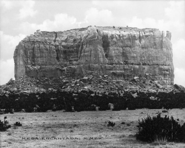 View across valley toward Mesa Encantada, a large stone formation. Caption reads: Mesa Encantada, N. Mex."
