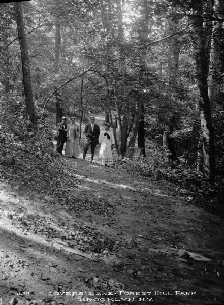 Two couples standing in the woods. Caption reads: Lovers' Lane, Forest Hill Park, Brooklyn, N.Y."