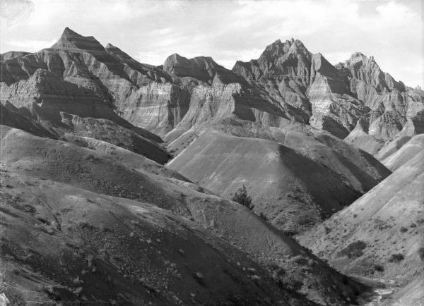 A view of the Badlands landscape. Rolling formations in the foreground give way to more extreme ones in the background.