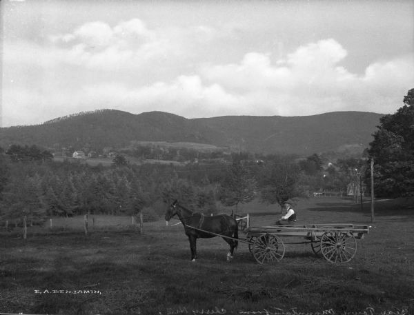 Bear Town Mountain from Cherry Hill. A man and a horse-drawn wagon are posing near homes that are scattered through the valley setting.