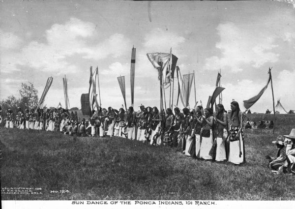 A large group of Ponca Native Americans in the Sun dance, at the 101 Ranch, one of the early focal points of the oil rush in northeastern Oklahoma. Text on the photograph reads, "Publ. & Copyright 1908 by H.H. Clake Oklahoma City, Okla. No. 124"