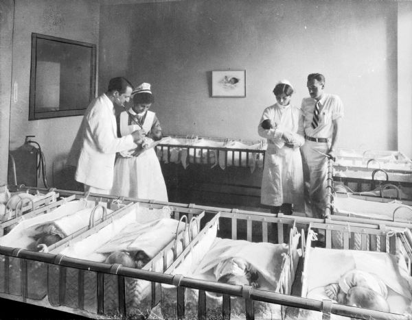 Two men, two women, and a number of newborns in the nursery at St. John's Hospital.