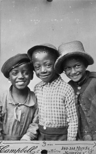 A portrait of three smiling African American boys wearing hats. Caption reads: "Campbells" and "340-344 Main St. Norfolk."