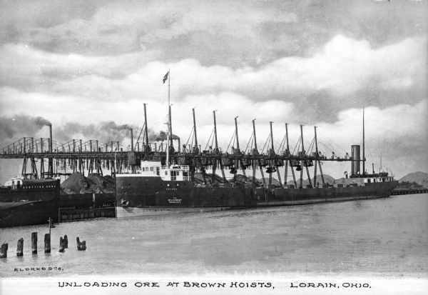 A view of ships laden with ore unloading at Brown Hoists. Caption reads: "Unloading Ore at Brown Hoists, Lorain, Ohio."