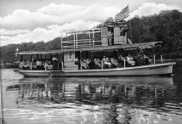 An excursion boat, "Shepard of the Hills," carrying many passengers and flying a U.S. flag near the front.