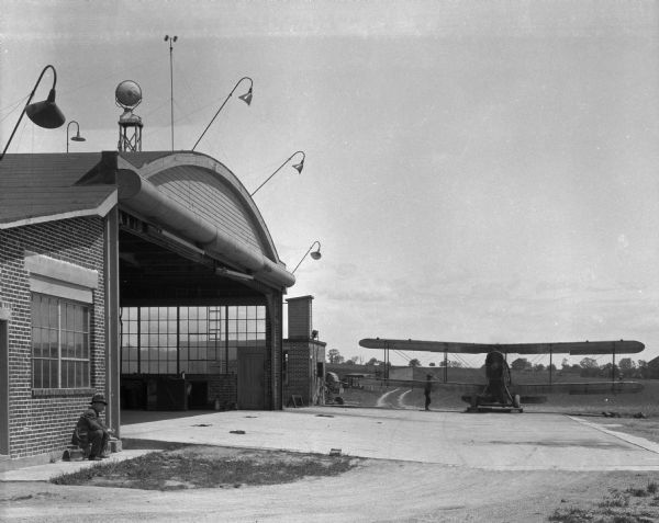 A view of an aerial mail station with an airplane and two men visible.