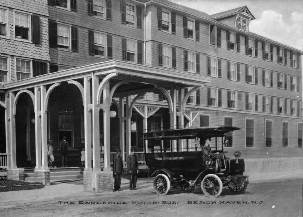 The Engleside Motor Bus parked in front of a large building, possibly a hotel. The driver is sitting in his seat, and other people, possibly bellhops, are standing behind the bus. Caption reads: "The Englside Motor-Bus, Beach Haven, N.J."
