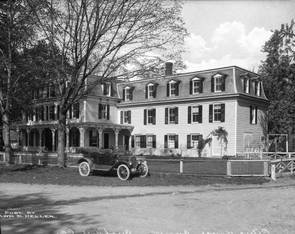 A view of the Peters House (hotel) annex exterior, and an automobile parked in front.