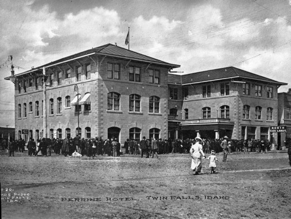 View across square toward the Perrine Hotel. There is a large crowd of people on the square. Caption reads: "Perrine Hotel, Twin Falls, Idaho."