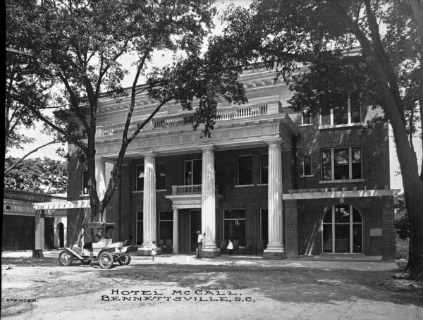 View toward the entrance of the Hotel McCall, with a parked automobile and several people standing in front. Caption reads: "Hotel McCall, Bennettsville, S.C."