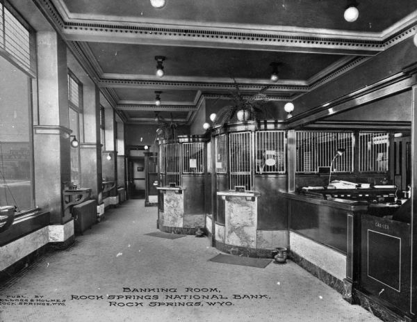 A view of the teller's windows inside the bank. Caption reads: "Banking Room, Rock Springs National Bank, Rock Springs, WYO."