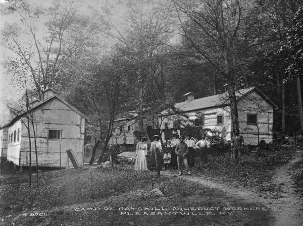 A view of a camp of the Catskill Aqueduct workers including three men, three women, and one child. Caption reads: "Camp of Catskill Aqueduct Workers, Pleasantville, N.Y."