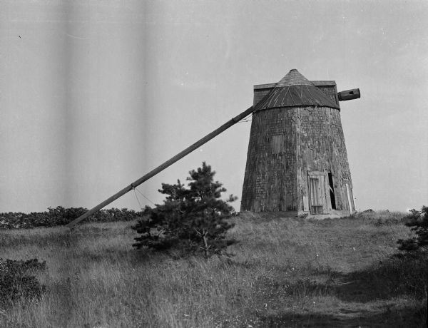 A view of "The Old Mill," a small thatched tower in an open field.