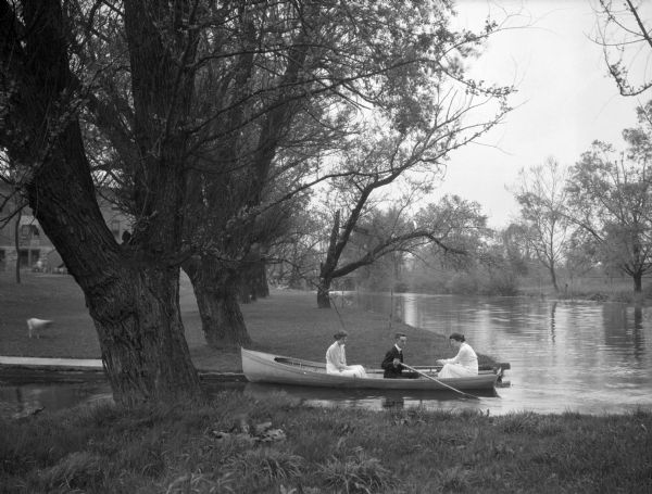 Three people aboard a small rowboat on the Conococheague creek at Wilson College.