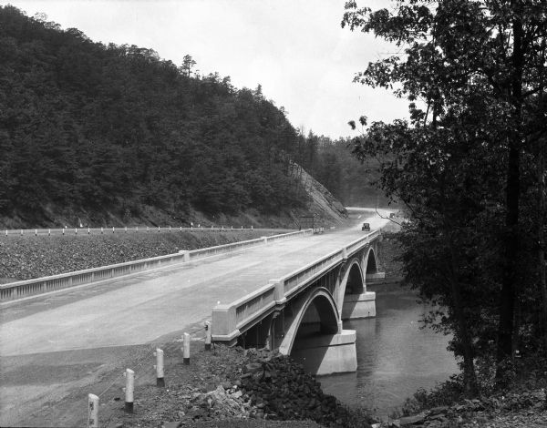 Elevated view of the Lincoln Highway, also known as the Juniata Bridge, or Juniata Crossing. View toward right side of bridge over a river, with tree-covered hills on the left.
