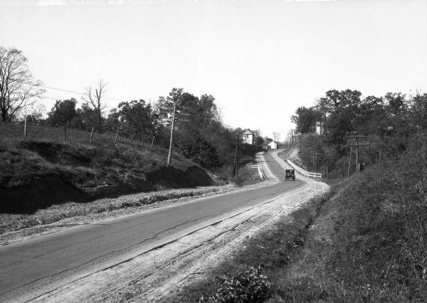 A view looking down the National Pike Highway, featuring an oncoming car, and building structures in the distance.