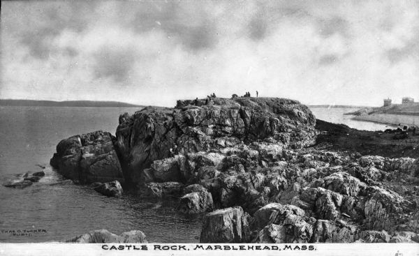Elevated view of Castle Rock, located on the coast, with numerous people looking out over the water. Caption reads: "Castle Rock, Marblehead, Mass."