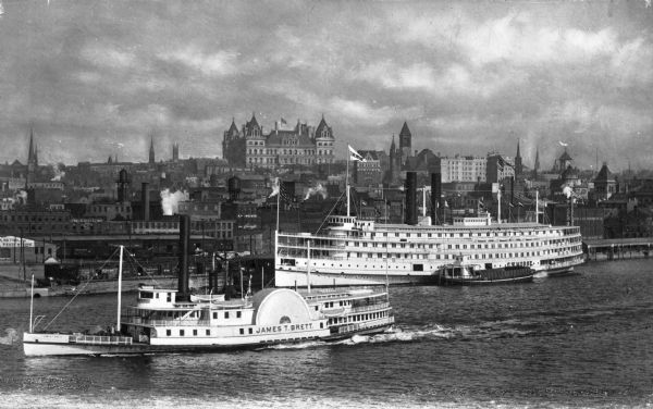 Elevated view of the two steamships, including the James T. Brett, on the Hudson River, with the central business district of the city in the background.