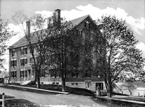 View across road toward a colonial-style, central brick dwelling located in the Shaker community, which was organized in 1794.