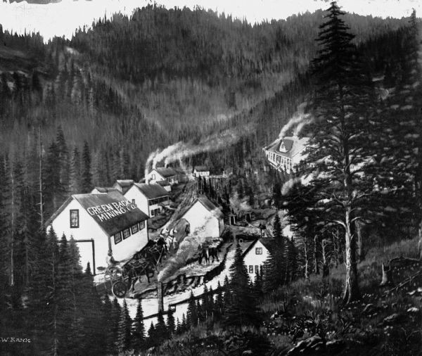Elevated view of Greenback Mining Company, located in a valley and surrounded by pine trees. There are mining buildings, a large house, and a man driving a team of horses pulling a cart.