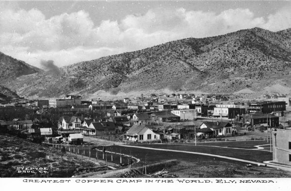 Elevated view of a copper mining camp with desert hills in the background. Caption reads: "Greatest Copper Camp in the World, Ely, Nevada."