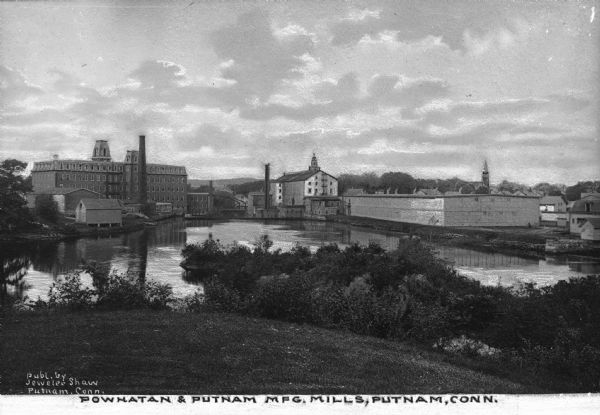 View across Quinebaug river of Powhatan and Putnam textile manufacturing mills. Caption reads: "Powhatan and Putnam Mfg. Mills, Putnam, Conn."