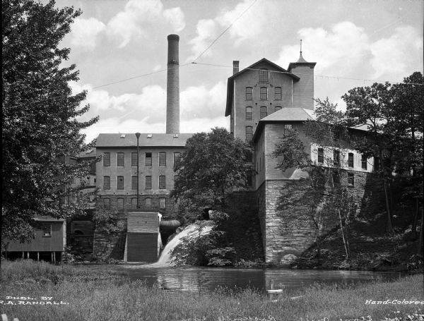 Waterside view of mill buildings including diverted water stream.