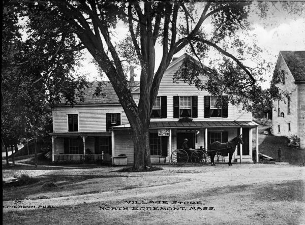 Village store with a large tree and a horse-drawn wagon in front. Caption reads: "Village Store, North Egremont, Mass."