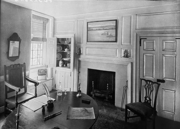 General George Washington's Headquarters. Room features a table set as a desk and chairs, fireplace, and built in cabinet with china.