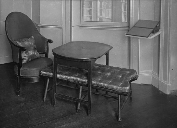 Interior view of Monticello, residence of Thomas Jefferson, featuring a chair, a small table and a cushioned bench arranged as an ottoman.