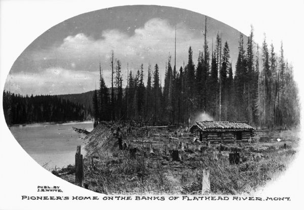 Oval cutaway of a view of a log cabin built on the banks of the Flathead river. The cabin is surrounded by stumps and the view includes the river and extensive forest. Caption reads: "Pioneer's Home on the Banks of Flathead River, Mont."