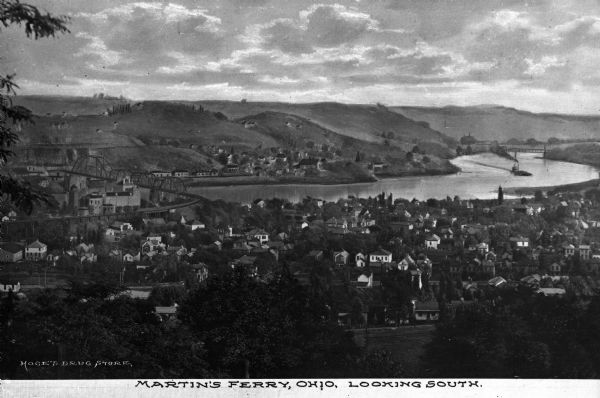 Elevated and distant southerly view of the Ohio river winding through a town. A bridge crosses the river in the foreground, and trees and houses are located on both banks. Caption reads: "Martin's Ferry, Ohio, Looking South."