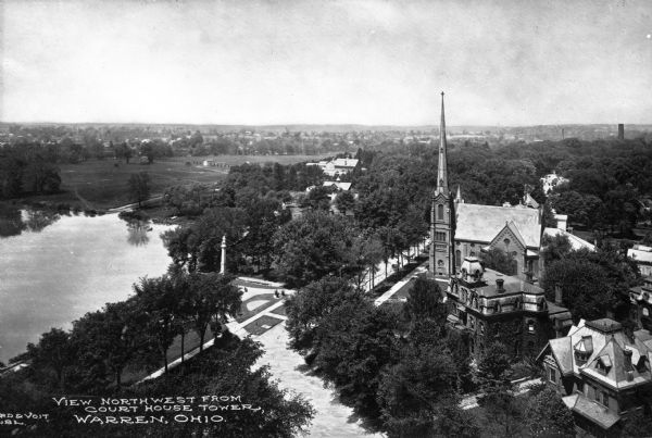 Elevated view of the First Presbyterian church and two mansions. The Mahoning river and a park is in the foreground, and other parts of the town stretch into the wooded distance. Caption reads, "View northwest from court house tower, Warren, Ohio."