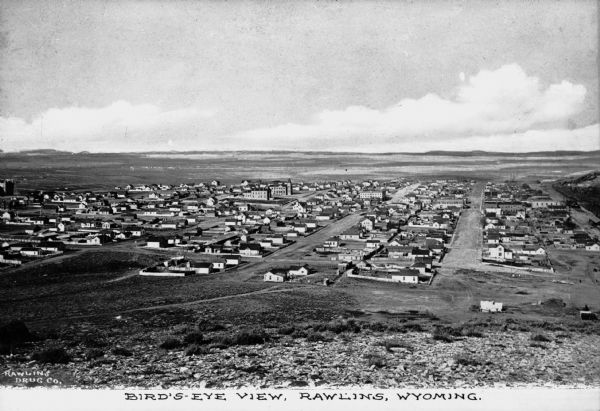 Distant view of a high plateau city with grids of streets and flatland stretching into the distance. Caption reads, "Bird's-Eye View, Rawling, Wyoming."