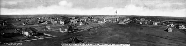 Panoramic elevated view of small town taken from the school house. The town is in flat country and has large expanses between houses. Caption reads: "Panoramic view of Chinook Mont From School House."