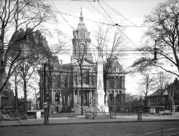 A corner view of the Courthouse and public square. Utility lines are visible. Baers Stationers.