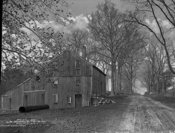 A view of the Old Mill on a road lined with trees.