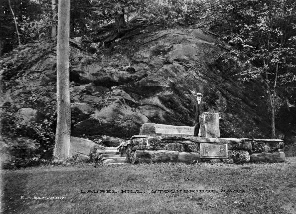 A view of the Sedgewick Memorial on Laurel Hill. The monument is in front of a large rock wall, and a man stands on the monument, posing for the camera. Caption reads: "Laurel Hill, Stockbridge, Mass."