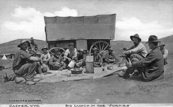 A dozen or so ranch hands sitting on the ground and eating on the plain. The chuckwagon is behind them. A large coffee pot and a bucket of rolls is on the blanket on the ground in the center. Caption reads: "Big Lunch in the 'Forties'."

A chuckwagon was originally a wagon that carried food and cooking  equipment on the prairies of the United States and Canada. The invention of the chuckwagon is attributed to Charles Goodnight, a Texas rancher who introduced the concept in 1866.