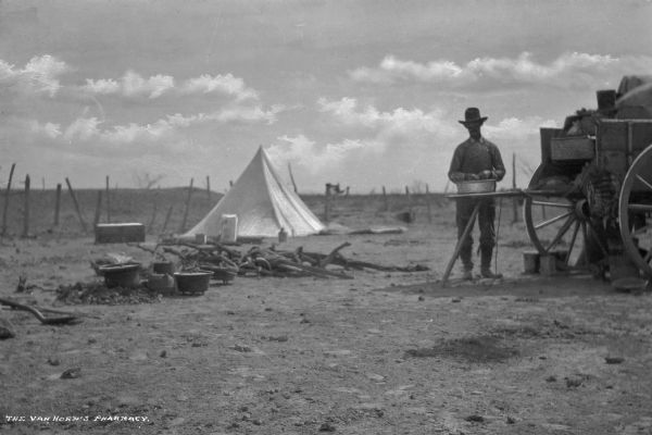 View of a camp with a cook standing at the back end of a chuckwagon with a large bowl in front of him. To the left is a pile of logs, along with some pots. In the background is a white tent near a fence.

A chuckwagon was originally a wagon that carried food and cooking  equipment on the prairies of the United States and Canada. The invention of the chuckwagon is attributed to Charles Goodnight, a Texas rancher who introduced the concept in 1866.
