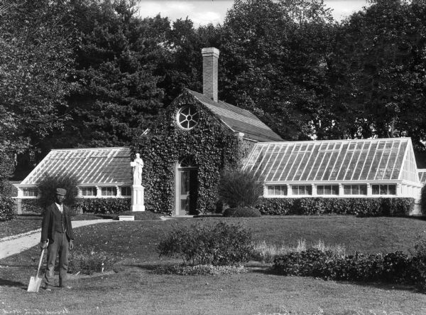 A man stands before the greenhouse on the campus of Woodstock College in Woodstock, Maryland. A religious statue is in front of the building's entrance.