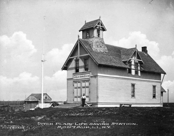 A view of the station and an outbuilding. A man stands in front of the building. Caption reads: "Ditch Plain Life Saving Station, Montauk, L.I., N.Y."