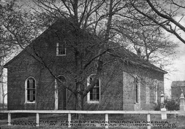 A view of the church surrounded by a fence. The building has arched windows and doorways. On the right are two gravestones. Caption reads: "First Presbyterian Church in America, at Rehoboth, near Pocomoke City, M.D."